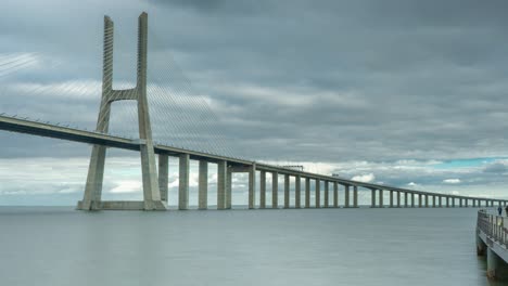 timelapse of the vasco da gama bridge in lisbon, portugal on a cloudy day with a near by walkway