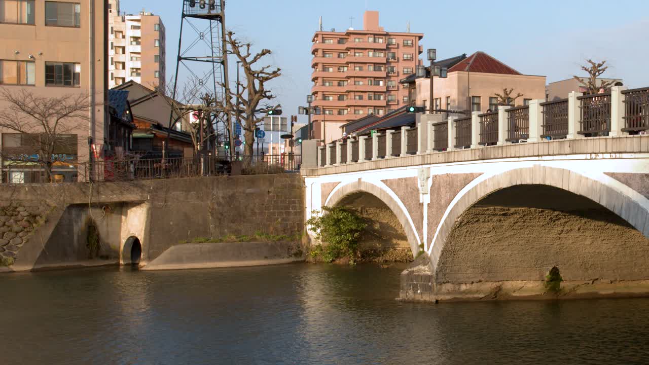 Kanazawa'da bir nehri geçen tarihi bir taş kemer köprünün durağan geniş çekimi.