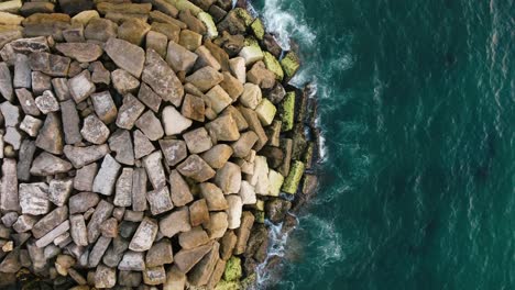 Bird-s-Eye-Shot-Of-Small-Waves-Crashing-On-Summit-Of-Rocks-In-Blue-Sea,Ericeira,-Portugal