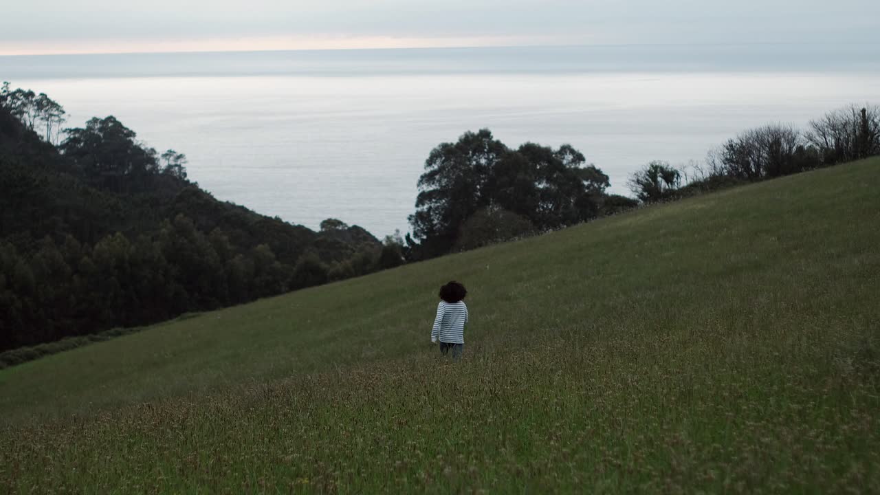 Long Hair Curly Man Running Happy in a Field of Flowers by the Sea. Happiness and Freedom Vibes