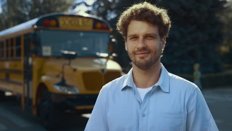 smiling man driver posing near bus close up. schoolbus operator looking camera.