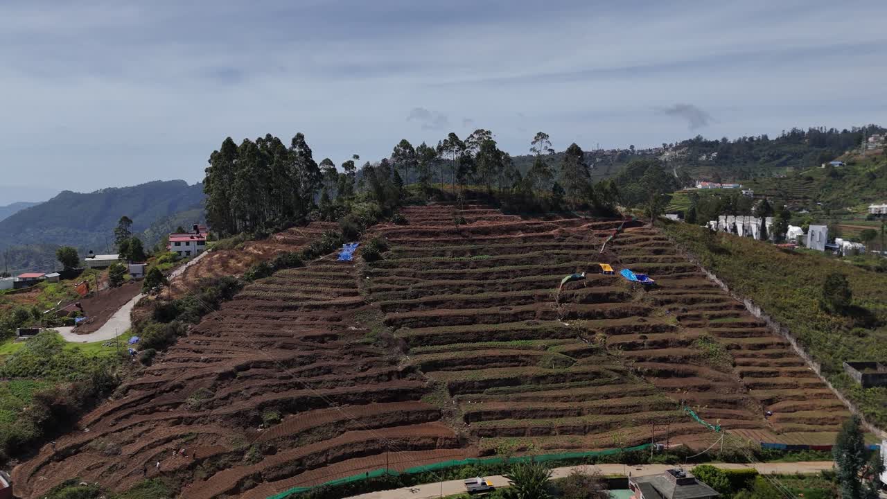 Aerial view of scenic slopes dotted with modern structures and rustic farmland