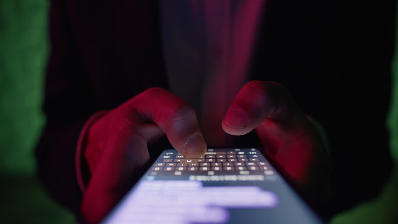 Primo piano di dita che scrivono un messaggio sullo schermo di uno smartphone con luci al neon in discoteca