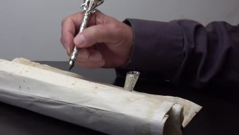 man writing with a quill pen on parchment paper