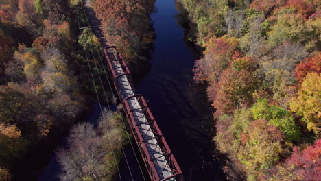 The-truss-bridge-over-the-Pawtuxet-River,-colorful-autumn-forests-on-the-banks