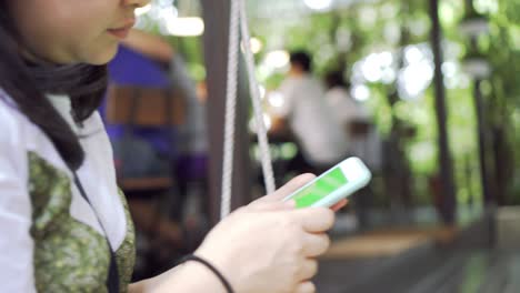 woman using smartphone on a swing