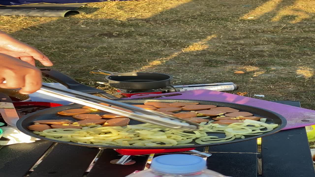 vertical footage, with friends camping and making breakfast of bread, sandwiches, sausages with a view of the clean Sermo reservoir.