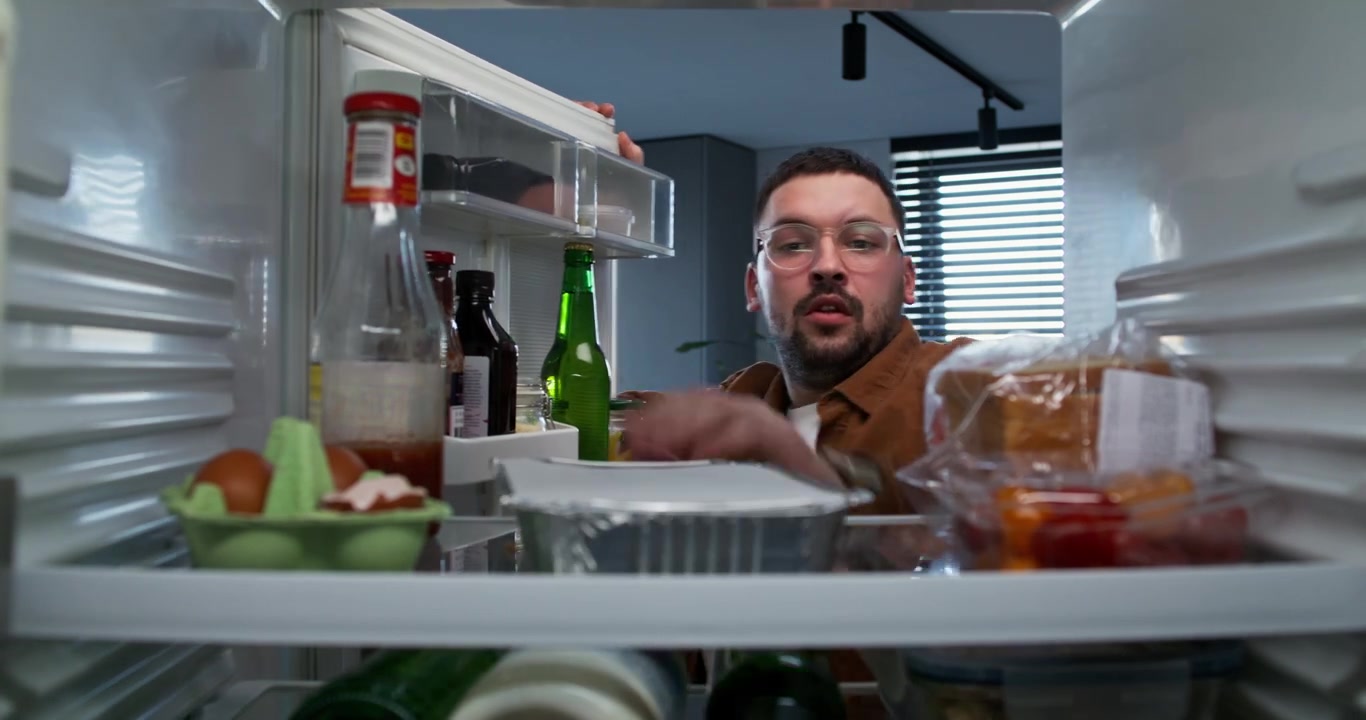 Uomo che guarda dentro un frigorifero