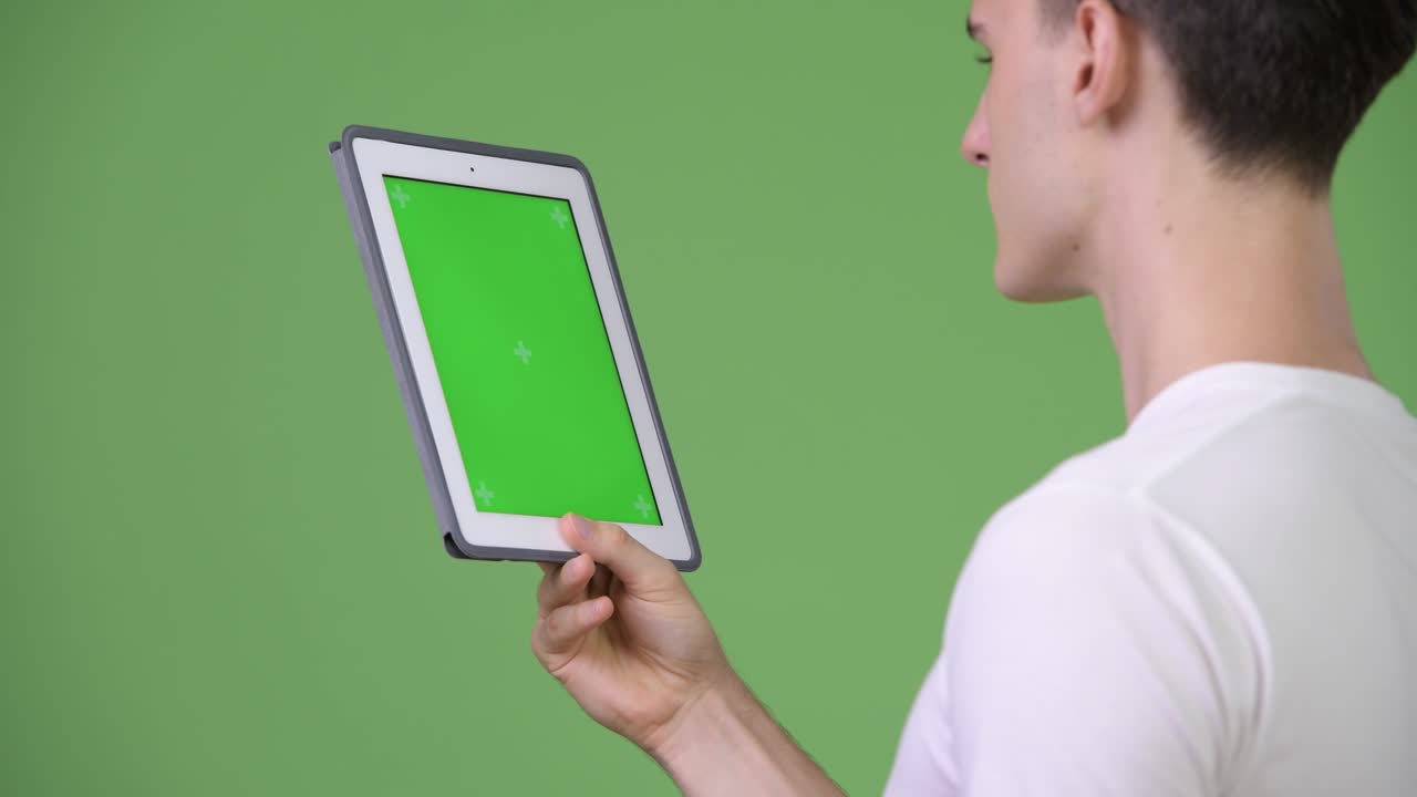 Profile view of young handsome man using digital tablet