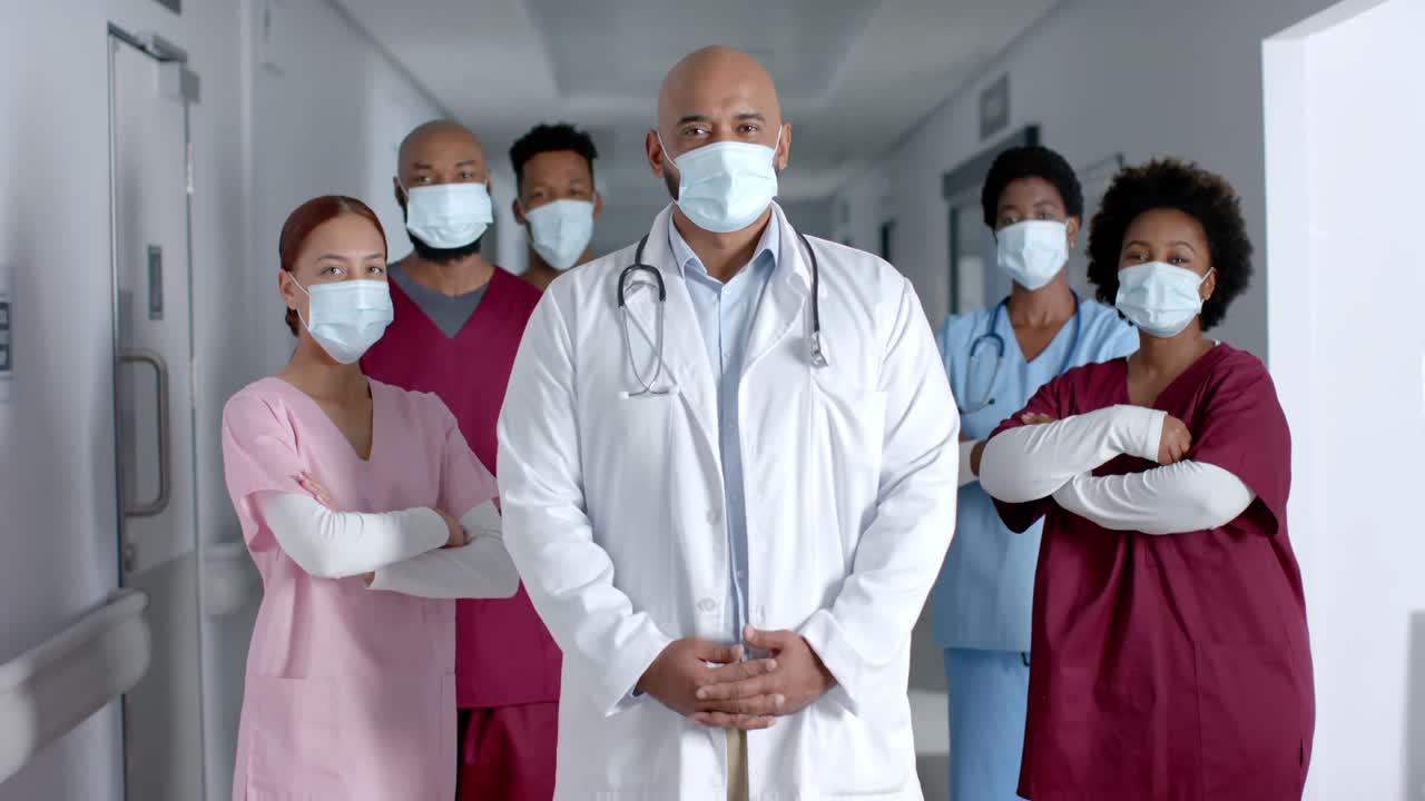 Portrait of happy diverse doctors wearing face masks in corridor, slow motion