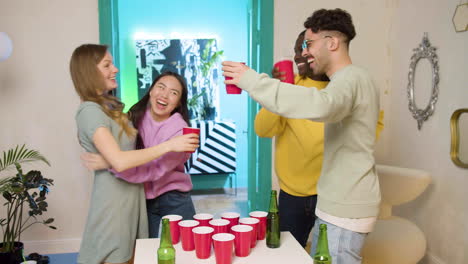 jóvenes amigos multiétnicos jugando pong de cerveza en casa