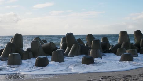 on a sunny day at the beach of hörnum waves are hitting tetrapods in slow motion