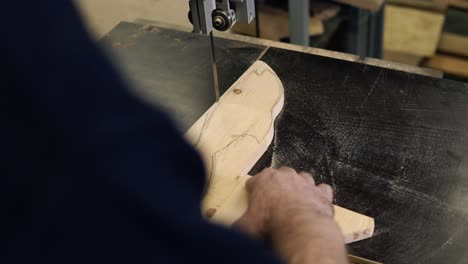 Imágenes-De-Primer-Plano-De-Las-Manos-De-Un-Hombre-Trabajando-Con-Una-Máquina-De-Corte-Eléctrica.-Imágenes-En-ángulo-Alto-De-Un-Hombre-Cortando-Un-Patrón-De-Madera-Con-Forma-De-Pez-Sobre-Una-Mesa.-Metraje-Desde-El-Hombro