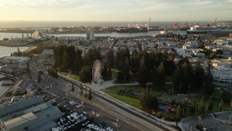 Aerial-establishing-shot-of-Ferries-Wheel-in-Esplanade-Park-in-front-of-large-Fremantle-Port-in-Perth,-Wester-Australia---Slow-drone-Forward-shot