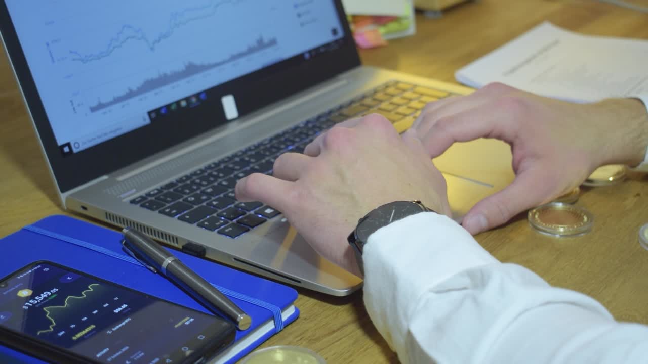 hombre de negocios profesional revisando el precio de mercado de las criptomonedas en su cuaderno mientras sostiene bitcoin dorado físico en sus manos