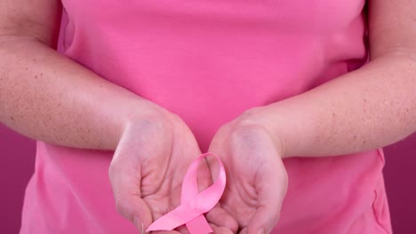 Video-of-midsection-of-caucasian-woman-holding-pink-cancer-awareness-ribbon