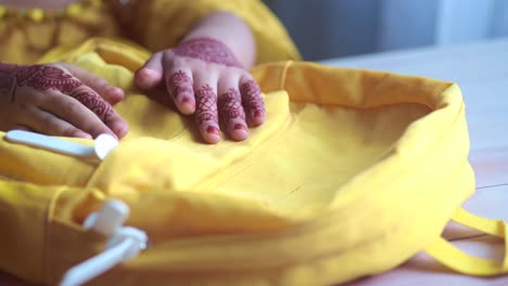 las manos del niño con henna en una mochila amarilla