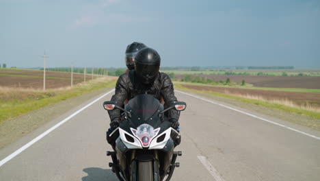 Couple-with-hardhats-travels-by-motorcycle-along-road