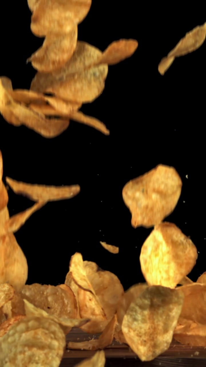 Crispy Potato Chips Falling and Piling Up on a Wooden Surface
