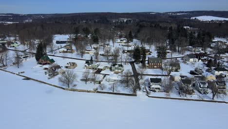 Luftdrohnenaufnahmen-Eines-Kleinen-Dorfes-In-Amerika-Auf-Einem-Zugefrorenen-See-Im-Winter-Im-Weststaat-New-York-Nach-Frischem-Schneefall