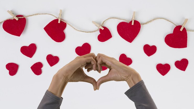 concepto del día de san valentín con las manos haciendo forma de corazón contra un fondo blanco con corazones rojos unidos a la cuerda