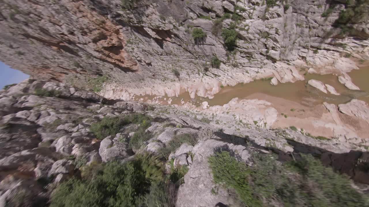 el vuelo fpv se sumerge rápidamente desde el borde del cañón accidentado hasta el río angosto debajo