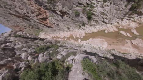 el vuelo fpv se sumerge rápidamente desde el borde del cañón accidentado hasta el río angosto debajo