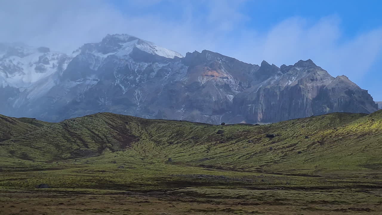 panorama del paisaje islandés, colinas cubiertas de nieve y campos verdes en un día nublado
