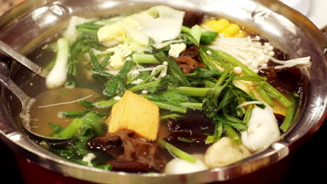 태국 방 ⁇  에 있는 식당 안 에서 토푸, 채소, 버섯, 향신료 를 넣고  ⁇   ⁇ 는 뜨거운  ⁇ 고기 양념 을 맛보는