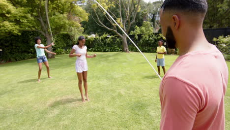 happy african american parents, son and daughter skipping in sunny garden, slow motion