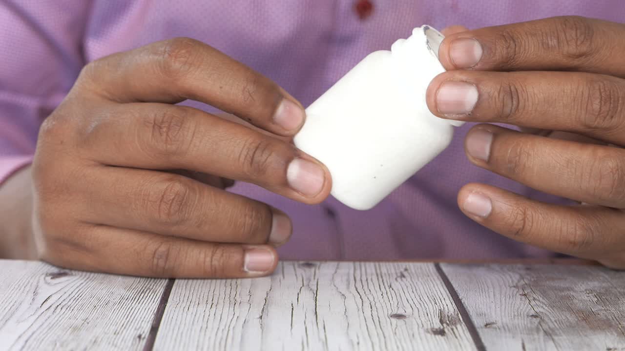 persona que sostiene un frasco de pastillas blancas