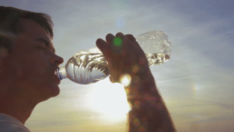 Junger-Mann-Trinkt-Wasser-Im-Freien-Bei-Sonnenuntergang