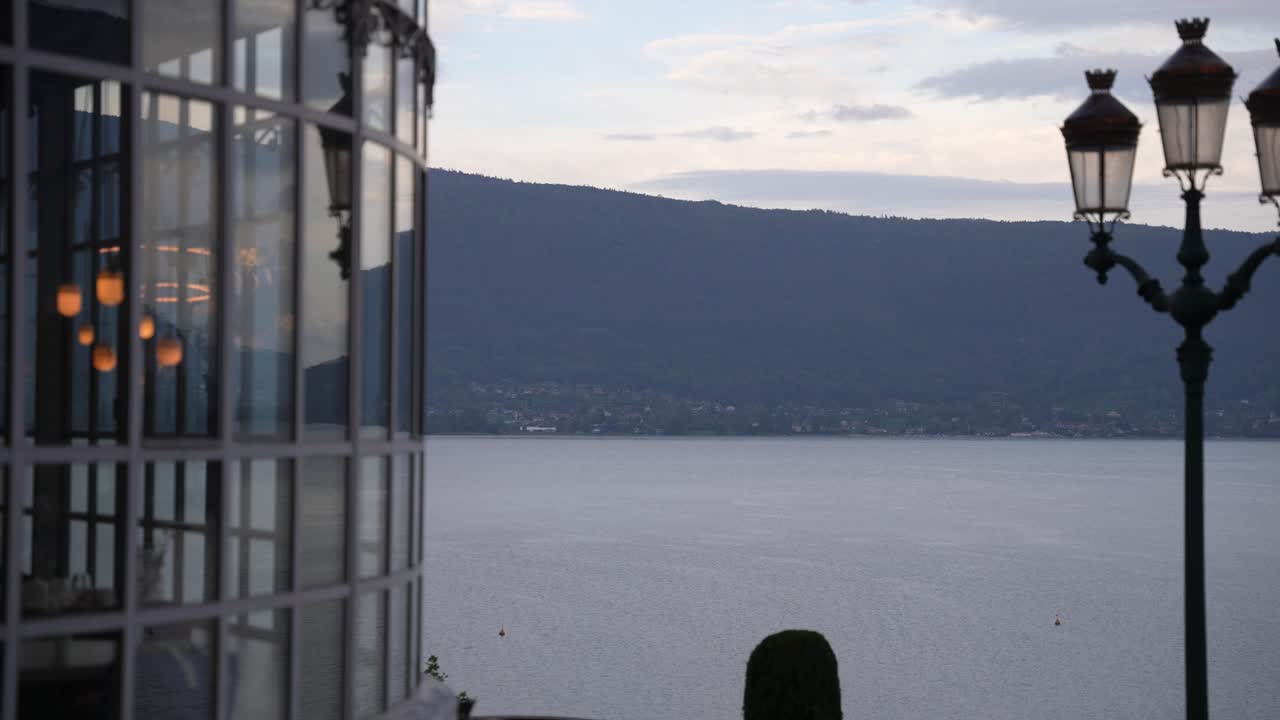 restaurante de ventana circular con vistas al lago annecy en francia al anochecer, toma cerrada
