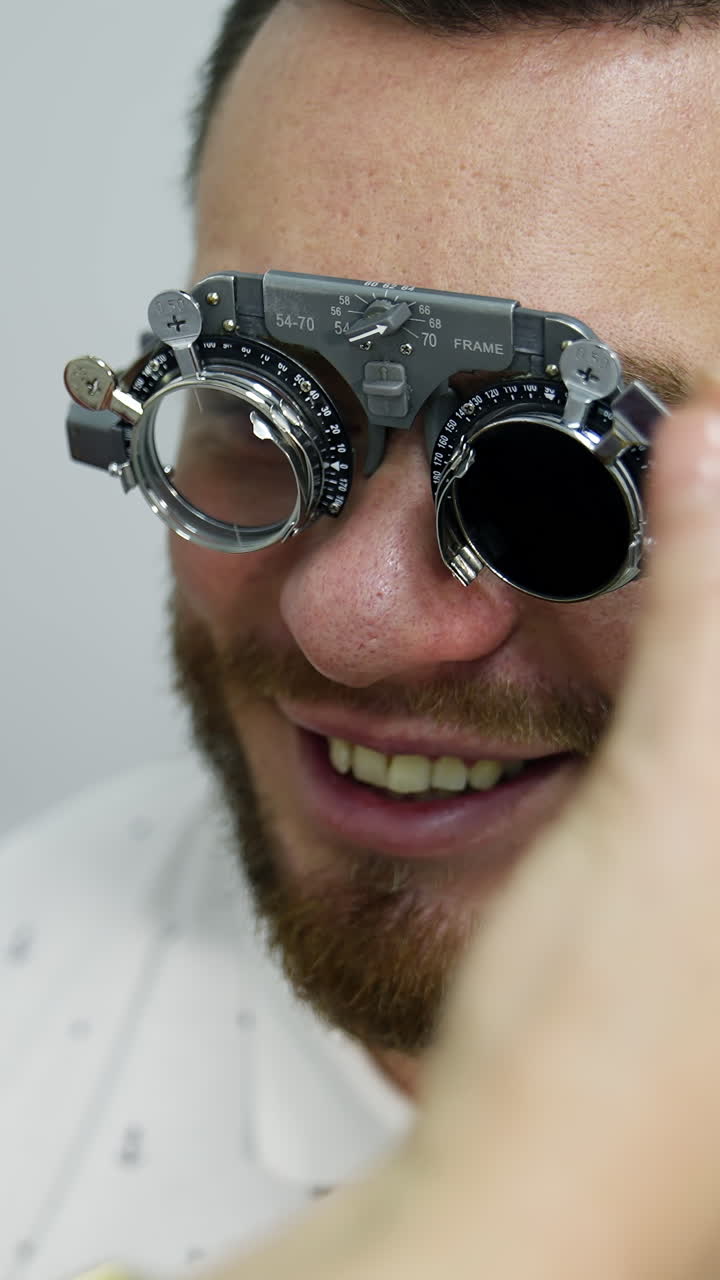 Smiling happy male patient in corrective testing glasses. Checking up eyesight in clinic. Handsome patient in ophthalmology. Vertical video