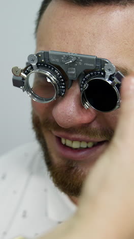 smiling happy male patient in corrective testing glasses. checking up eyesight in clinic. handsome patient in ophthalmology. vertical video