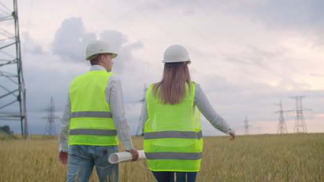 back two the engineer and the controller with a tablet pc and the drawings are about lines and transmission towers and discuss the expansion plan and transportation energy for towns and cities.