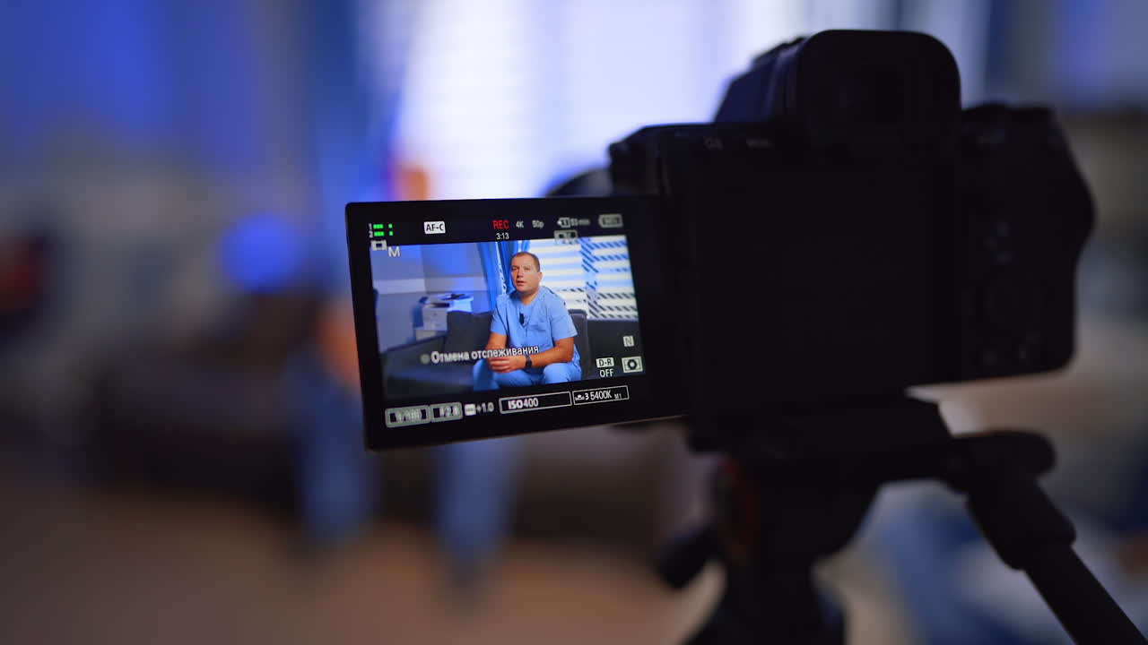 Confident Caucasian male doctor making a video. Camera records content for medical vlog. Selective focus