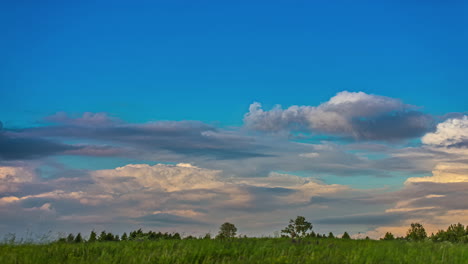 shot of white cirrus cloud movement in timelapse across bllue sky over green grasslands on a cloudy day