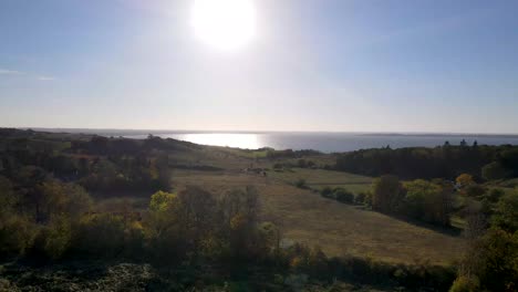 Aerial-view-of-the-incredible-beautiful-coastline-with-blue-sky-and-the-sun-in-Odsherred,-Zealand,-Denmark