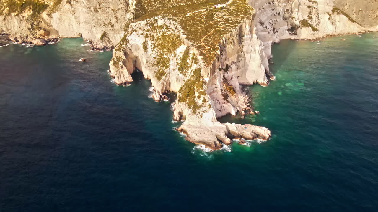 Aerial drone view of the Ionian Sea coast of Zakynthos, Greece. Rocky ridge, sparce vegetation, blue water. Sunset