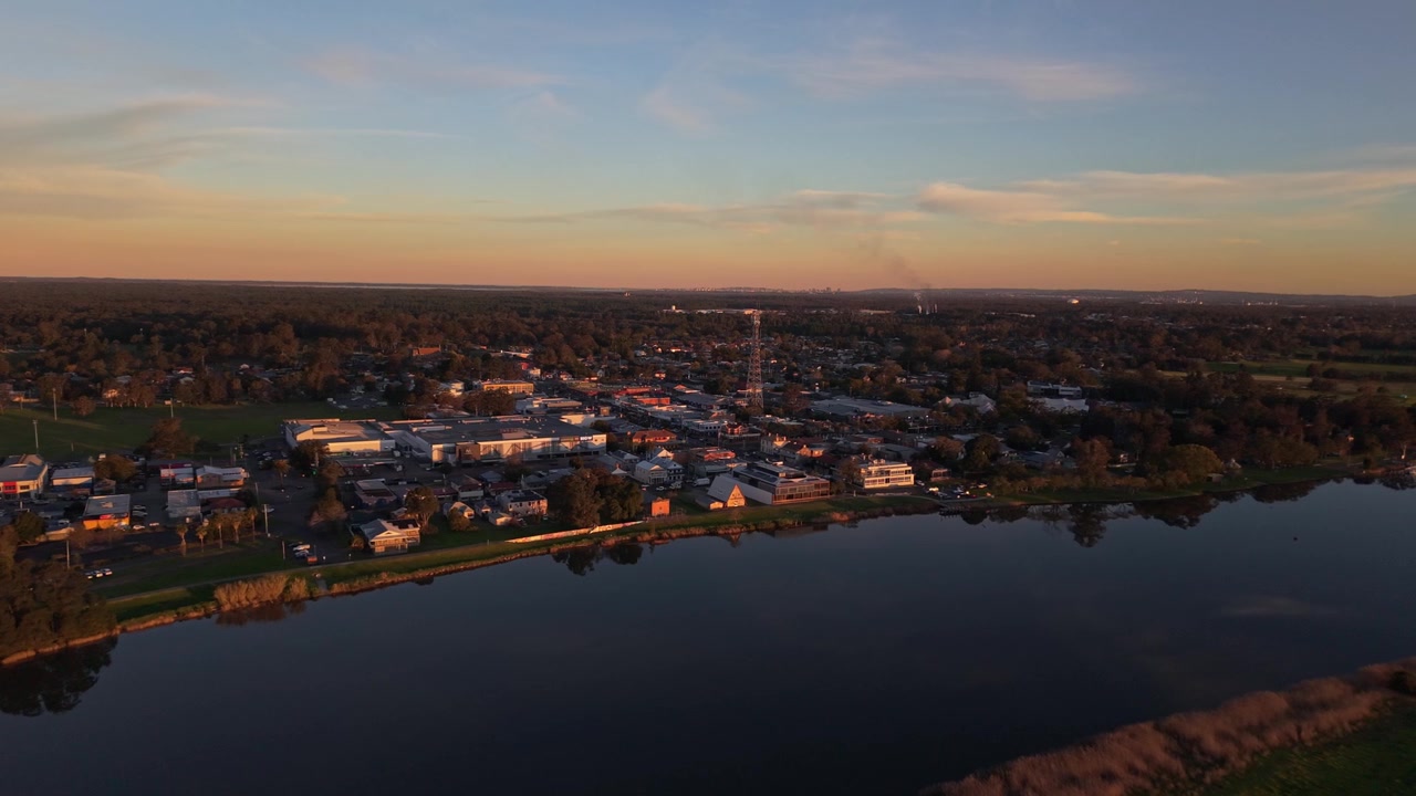 Raymond Terracen kaupunki rajautuu Hunter-jokeen auringonlaskun aikaan Uudessa Etelä-Walesissa, Australiassa, ilmakuva vetäytyy taaksepäin kultaisella tunnilla.