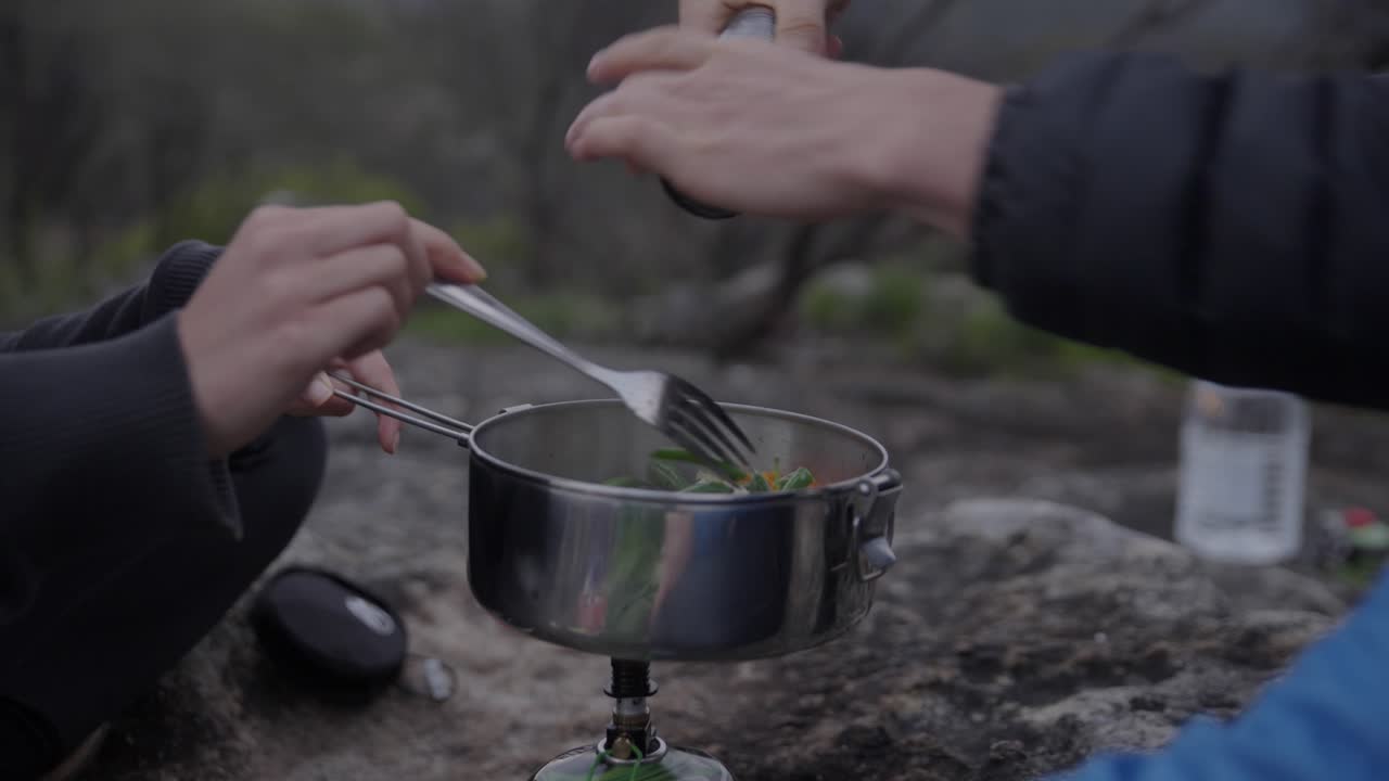 山でのキャンプ、湯気を立てて調理され、味付けされる料理