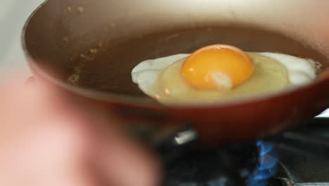 romper un huevo en una sartén con mantequilla caliente para cocinar para el desayuno