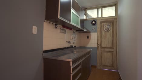 slow glide reveals sleek, narrow kitchen’s functional layout and contemporary design, framed by entryway. ideal for compact space showcases.