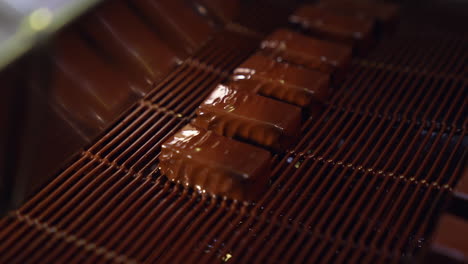 sweets coming out of chocolate pouring and being blown by the air to make ripples. delicious chocolate candies production. close up.