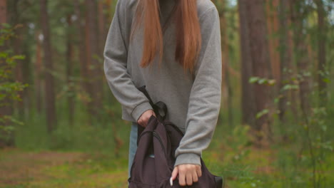 dos jóvenes excursionistas caminan a través de un bosque tranquilo, llevando mochilas y disfrutando del paisaje, se acercan a un árbol caído, y la dama con el suéter gris comienza a abrir su bolsa negra