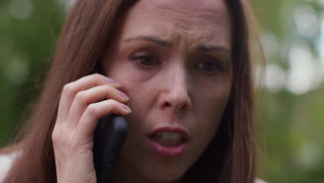 close up of stressed or angry woman outdoors with financial worries about cost of living crisis debt and paying bills talking on mobile phone