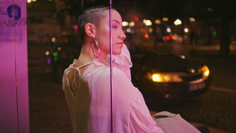 mujer elegante en la parada de autobús nocturna