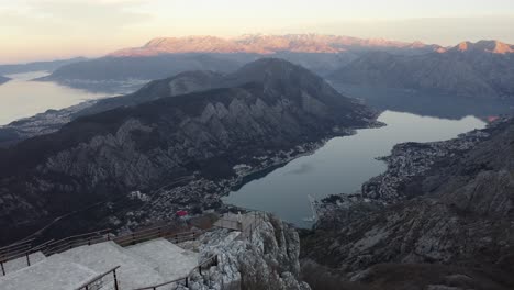 Vogelperspektive-Auf-Die-Bucht-Von-Kotor,-Die-Einen-Touristen-Auf-Einer-Holzterrasse-Zeigt,-Der-Die-Herrliche-Aussicht-Genießt