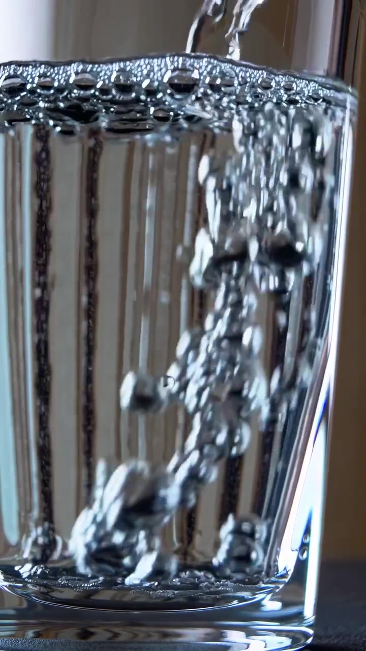 Close-up of Fresh Water Pouring into a Clear Glass with Bubbles